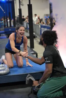 Ashley Kiser laughing on the platform as Coach MJ, kneeling, shakes her hand