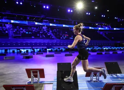 Corinne Thompson running across tilted steps under arena lights