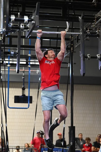 David Kiser in a red Team Ninja shirt hanging from a bar