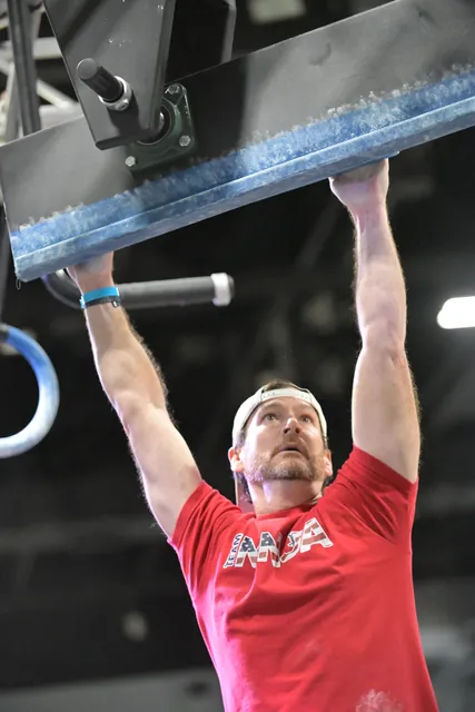 David Kiser hanging from the edge of a spinning beam, looking up