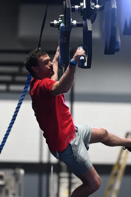 David Kiser swinging between hanging grips