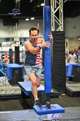 David Kiser in a stars-and-stripes tank swinging around a padded pole
