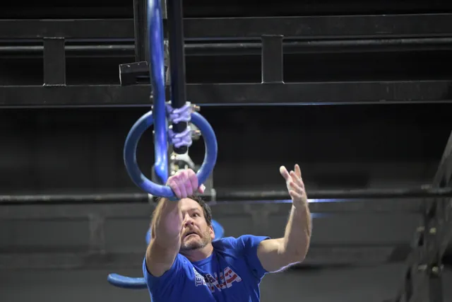 David Kiser in a blue Team Ninja shirt catching a hanging ring