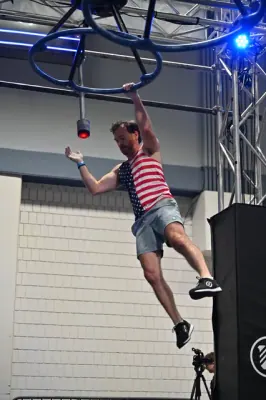 David Kiser swinging one-handed from a spinning ring wheel
