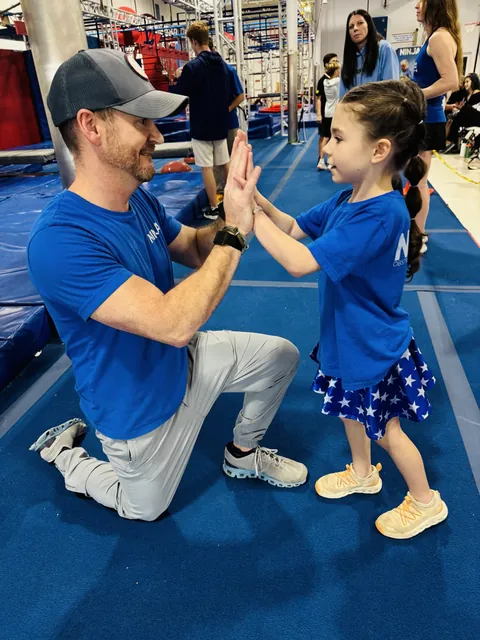 David Kiser kneeling to high-five his daughter Elliot on the NinjaFit course
