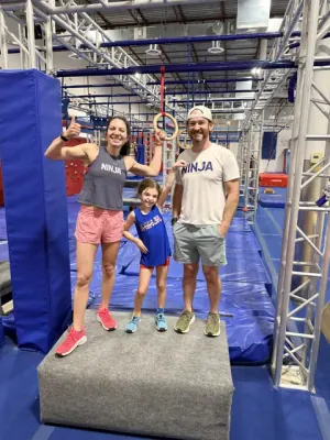 Ashley, Elliot and David Kiser smiling on a platform on the NinjaFit course