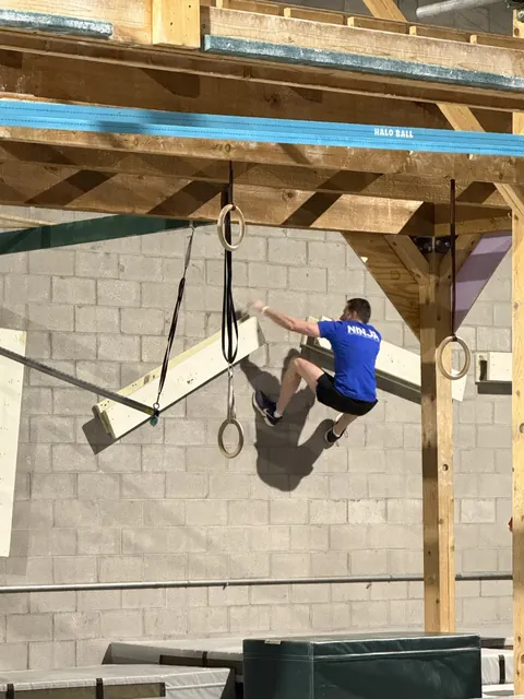 Nicholas Parker in a blue NinjaFit shirt jumping between angled boards
