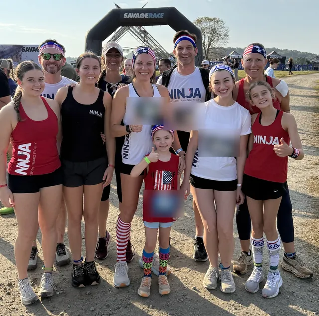 NinjaFit athletes of all ages smiling and giving thumbs up in front of the Savage Race arch