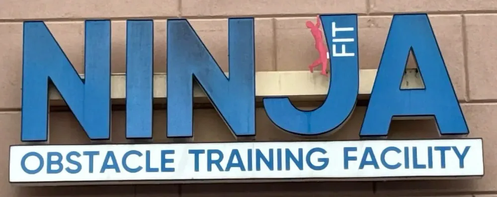 The blue NINJA FIT Obstacle Training Facility sign on the front of the gym