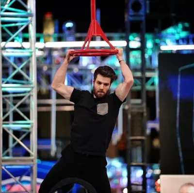 Tyler Gillett hanging from a red ring obstacle