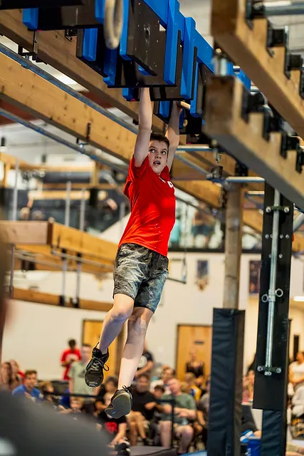 Coach Jackson McGee competing on the hanging grips in front of a crowd