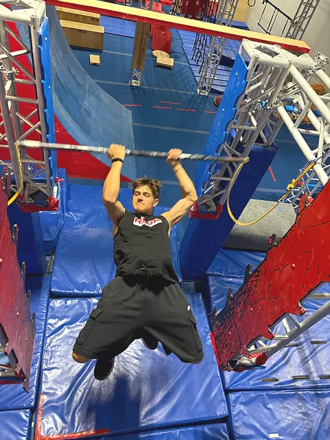 Coach Aiden Burley hanging from a bar between the cliffhanger walls