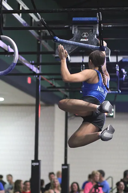 Coach Emily Fisher swinging between rings at a ninja competition