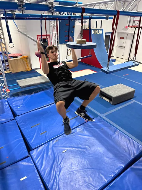 Coach Aiden Burley on the swinging rings course