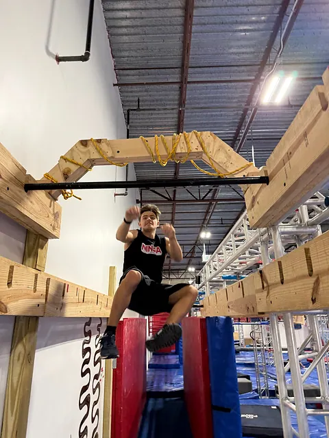 Coach Aiden Burley driving his knees through a bar swing
